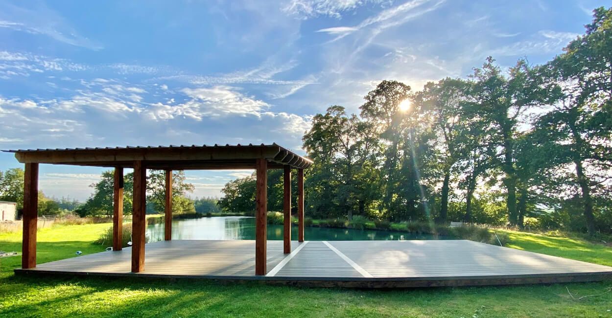 large decking with pergola set on the edge of a lake