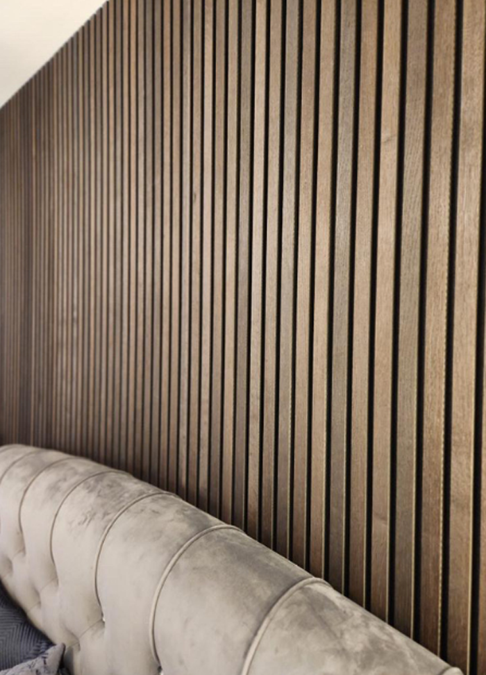 Slatted wood panels going up to the ceiling behind a headboard