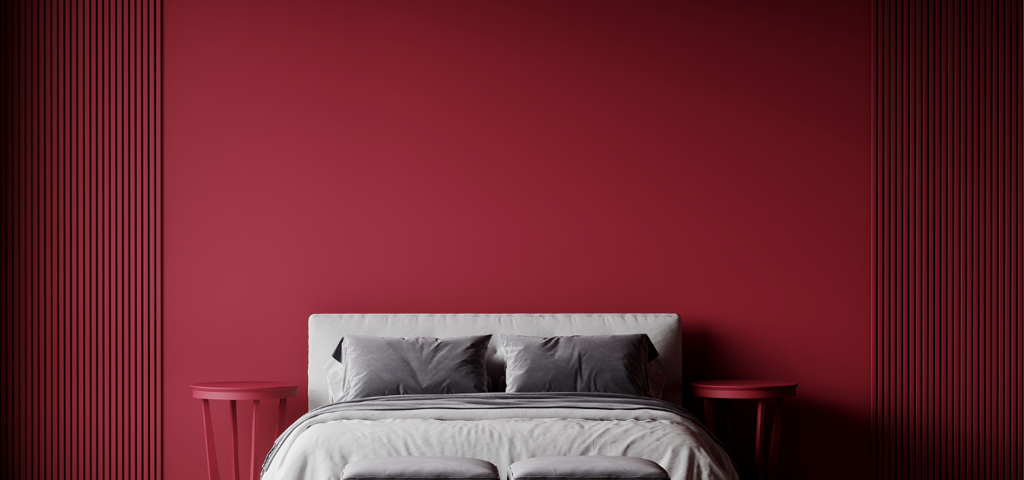 Dark red wall and slatting on either side of a grey double bed