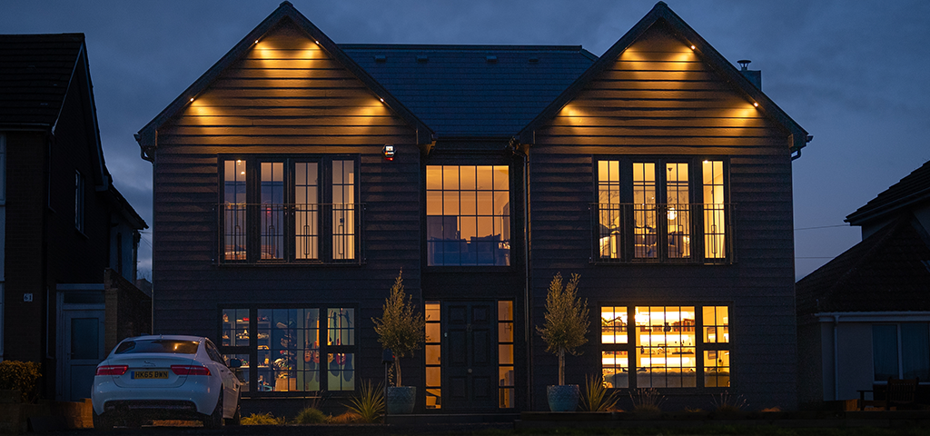 Modern mid-century home with Cladco black fibre cement lap cladding boards lit at dusk