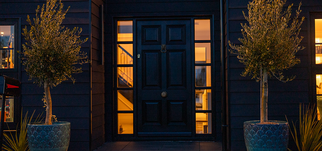 Close-up of black front door and entrance framed by Cladco black fibre cement lap cladding.