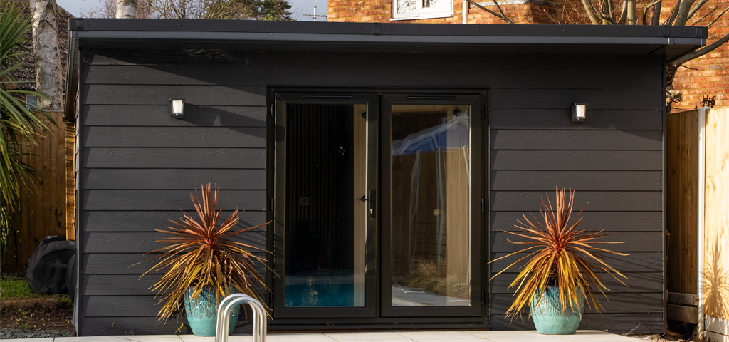 A matching outbuilding also clad in Cladco black fibre cement lap wall cladding.