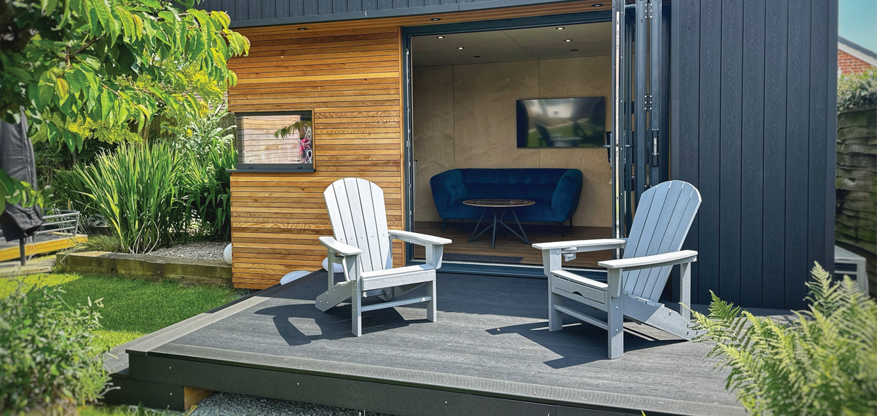 A garden outbuilding featuring a composite decking area and matching garden furniture